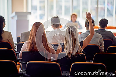 A young business woman wants to ask a question during a business conference. Business, people, meeting, company Stock Photo