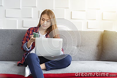 Young business woman working on sofa with mobile and laptop. Small business and modern technology concept Stock Photo