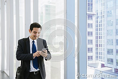 Young businessman in airport. Casual urban professional business man using smartphone smiling happy inside office building. Stock Photo
