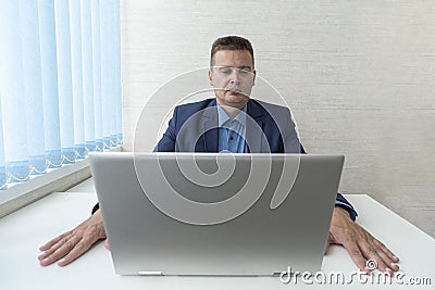 Young businessman concentrating on computer work, looking at laptop screen, thinking. focused reading of information on Stock Photo