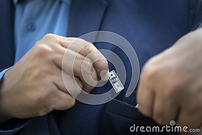 A young businessman guy holds a small bill in his hand as a symbol of declining income. Small salary concept. The Stock Photo