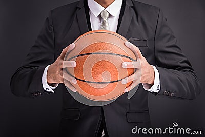 Young businessman holding basketball ball Stock Photo