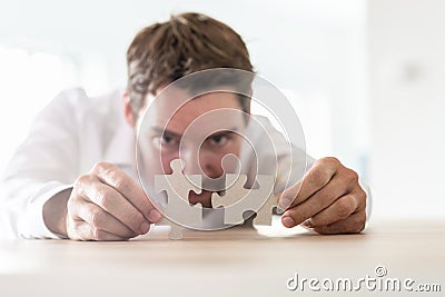 Young businessman joining two matching puzzle pieces Stock Photo