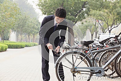 Young businessman locking up his bicycle on a city street in Beijing Stock Photo