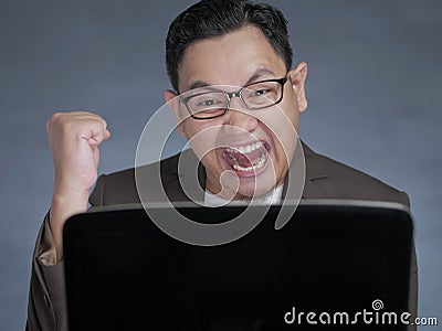 Young Businessman Looking at Laptop, Winning Gesture Stock Photo