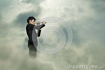 Young businessman looking through telescope in a dreamlike cloud Stock Photo