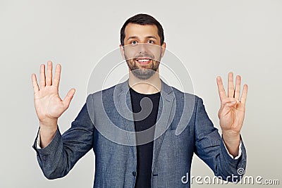 Young businessman man with beard smiling, showing number nine with fingers on hand, smiling confidently and happily, looking into Stock Photo