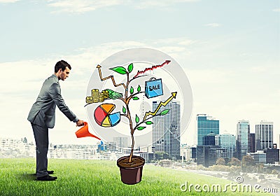 Young businessman outdoors watering drawn growth concept with can Stock Photo