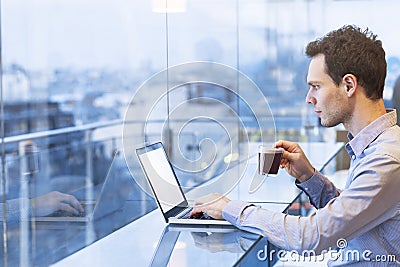 Young businessman reading emails on laptop in modern coffee shop Stock Photo