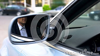 Young businessman reflecting in wing mirror of car, driving to office meeting Stock Photo