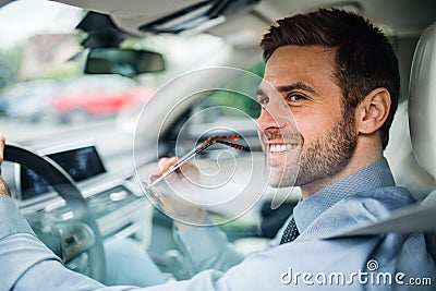 Young businessman with shirt sitting in car. Shot through glass. Stock Photo