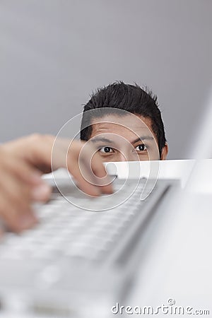 Young businessman spying on someone else`s laptop. Conceptual image Stock Photo