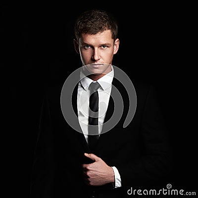 Young Businessman standing on black background. handsome Man in suit and tie Stock Photo