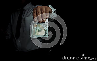 Young businessman standing holding money and handcuffs attached to his arm Concept Corrupt police, bad cop, bribe police Stock Photo