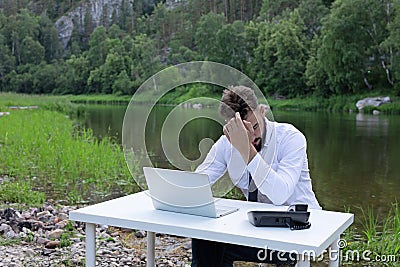 Young businessman in state of stress, fatigue and headache, he holds hand to his head. Young man having trouble studying Stock Photo