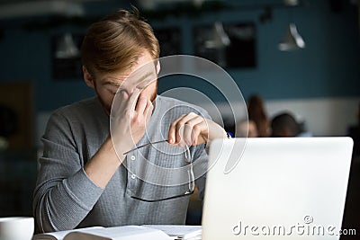 Young businessman taking off glasses feeling eyestrain tired of Stock Photo