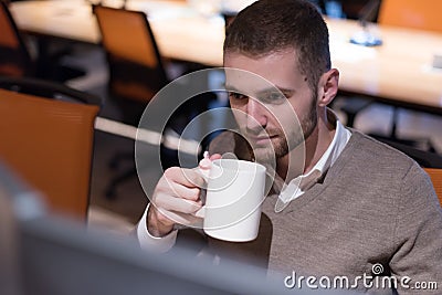 Young businessman working on computer in co work space. Coworking process, businessman working at modern office, drinking tea Stock Photo