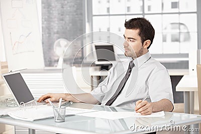 Young businessman working in office using laptop Stock Photo