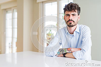 Young businesss man sitting on white table skeptic and nervous, frowning upset because of problem Stock Photo