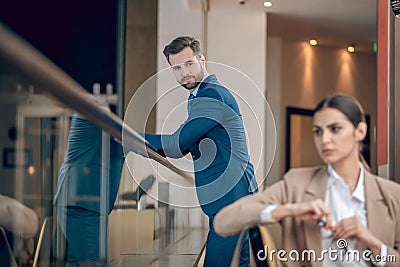 Young businesswoman in beige jacket feeling anoyed by her male colleague Stock Photo