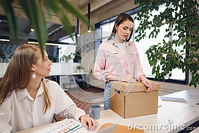 Young businesswoman holding box of personal belongings about to leave office after quitting job Stock Photo