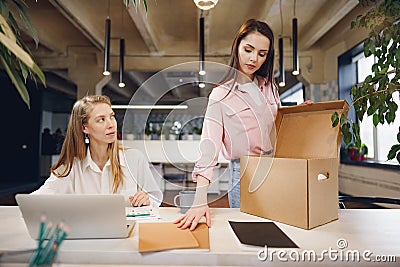 Young businesswoman holding box of personal belongings about to leave office after quitting job Stock Photo