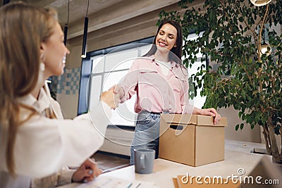 Young businesswoman holding box of personal belongings about to leave office after quitting job Stock Photo