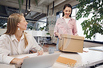 Young businesswoman holding box of personal belongings about to leave office after quitting job Stock Photo