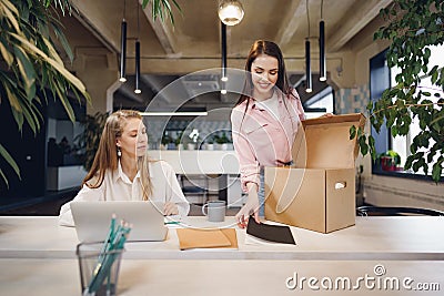 Young businesswoman holding box of personal belongings about to leave office after quitting job Stock Photo