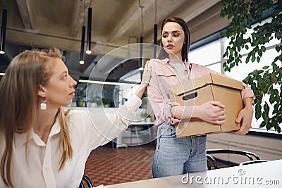 Young businesswoman holding box of personal belongings about to leave office after quitting job Stock Photo