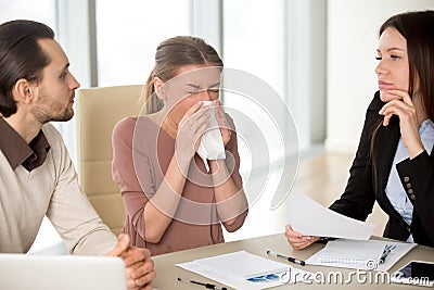 Young businesswoman holding handkerchief sneezing during meeting Stock Photo