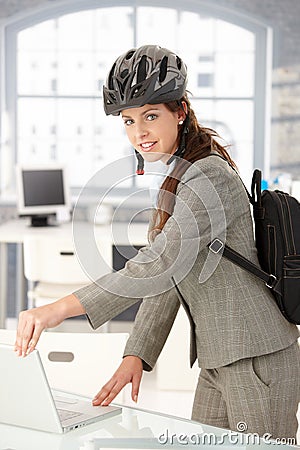 Young businesswoman leaving office by bike smiling Stock Photo