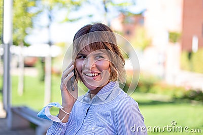 Young businesswoman in park calling by phone looking away Stock Photo