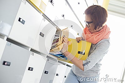 Young businesswoman removing file from locker at creative office Stock Photo