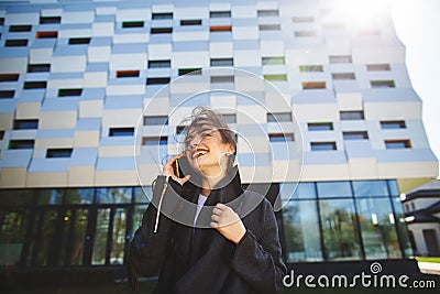 Young businesswoman speaking on mobile phone during outdoor coffee break, near office building. Communication concept Stock Photo