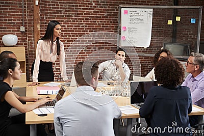 Young Businesswoman Standing And Leading Office Meeting Around Table Stock Photo