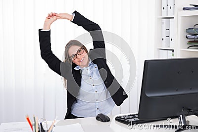 Businesswoman Stretching At Desk Stock Photo