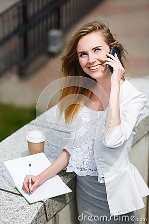 Young businesswoman talking on cellphone while walking outdoor Stock Photo