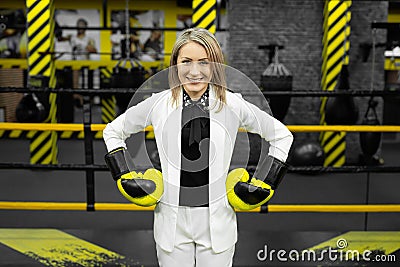 Young businesswoman in a white suit and boxing gloves in a boxing ring. Stock Photo