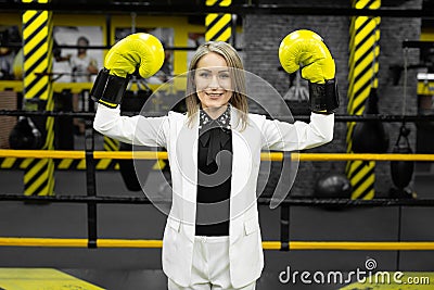 Young businesswoman in a white suit and boxing gloves in a boxing ring. Stock Photo