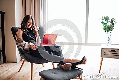 Young businesswoman work at home. Cheerful nice model waving with hand. Sitting on chair. Busy brunette has video chat Stock Photo