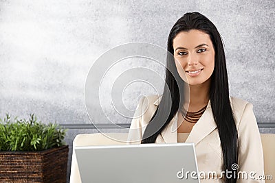 Young businesswoman working on laptop smiling Stock Photo