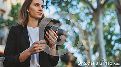 Young businesswoman writes messages on smartphone while walking in a Barcelona Park on Sunny day, professional financier girl Stock Photo