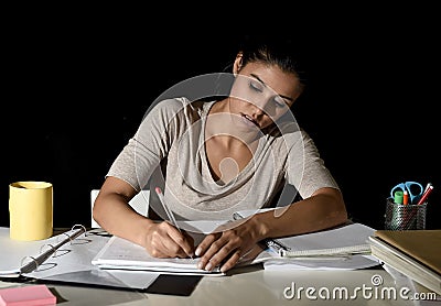 Young busy beautiful Spanish girl studying at home late night looking preparing exam writing on notepad Stock Photo