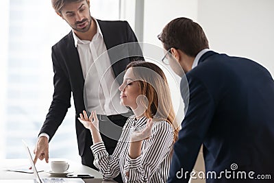 Young calm woman meditating in workplace, ignoring colleagues. Stock Photo