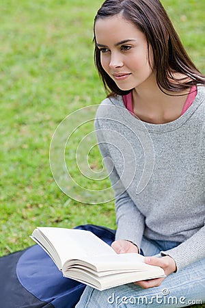 Young calm woman reading a book in a park while looking away Stock Photo