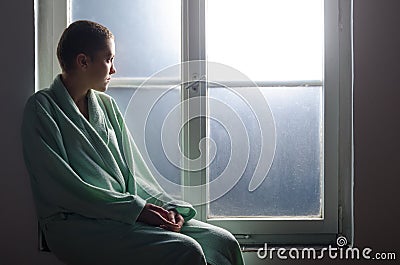 Young cancer patient sitting in front of hospital window Stock Photo