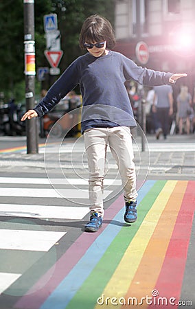 Young careful child walking through the rainbow crosswalk, halo effect Stock Photo