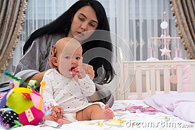 Young careful mother dressing baby in the morning. Stock Photo