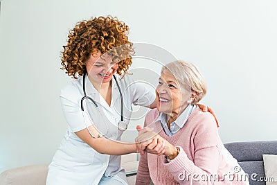 Young caring lovely caregiver and happy ward. Image of caregiver and senior resting in the living room. Smiling caregiver taking Stock Photo
